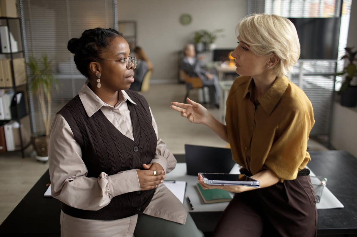 Two professional women collaborating over documents in a modern office, building an institution together