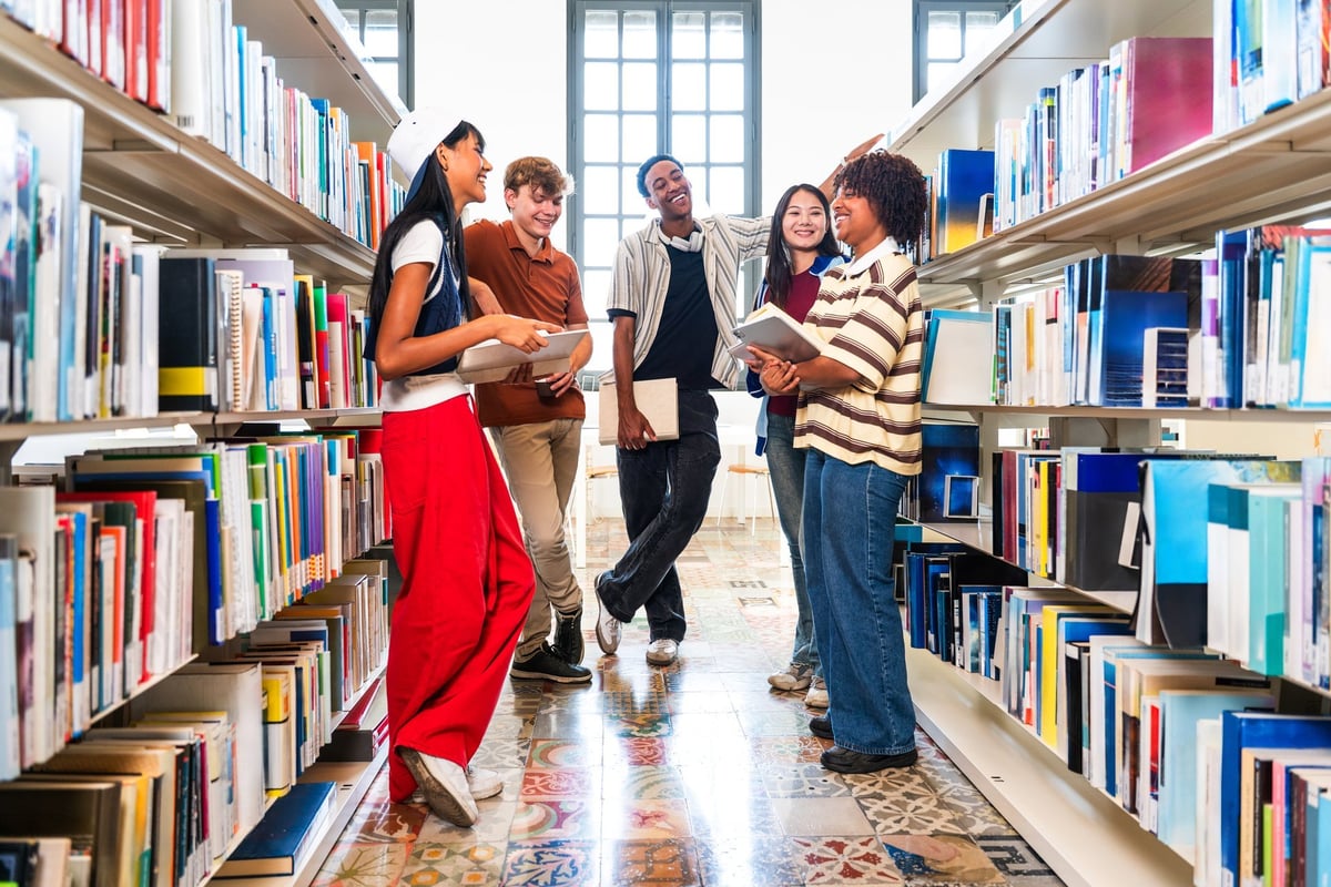 A multiethnic group of scholars collaborating while researching together in a bright university library